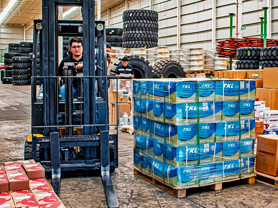 Montacargas operando en un almacén con cajas apiladas de un proveedor de refacciones TKL