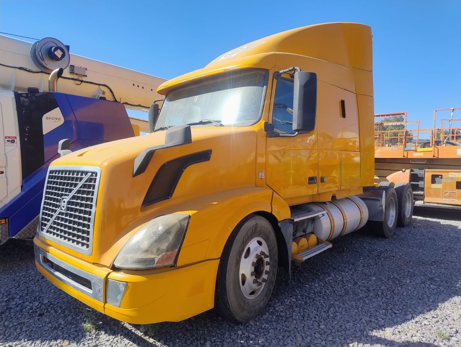 Perspectiva diagonal de Volvo VNL 2015 amarillo, resaltando su diseño aerodinámico y rines de aluminio.